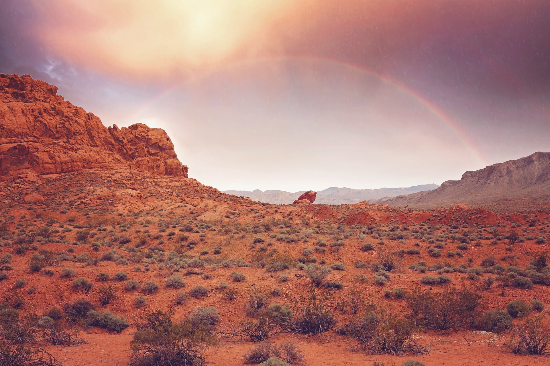 A view of a rainbow over a red desert landscape