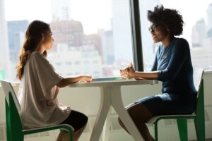 Two People Meeting by Window two women having a conversation